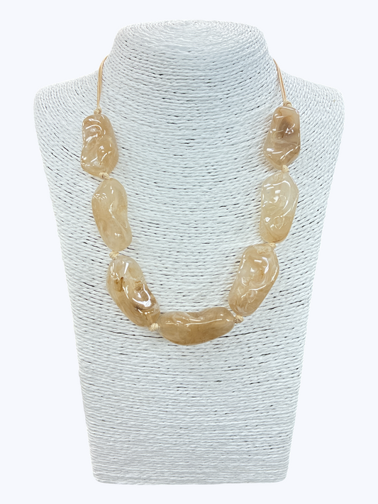 Beige textured bead statement necklace with glossy organic-shaped beads and minimalist cord design on mannequin display