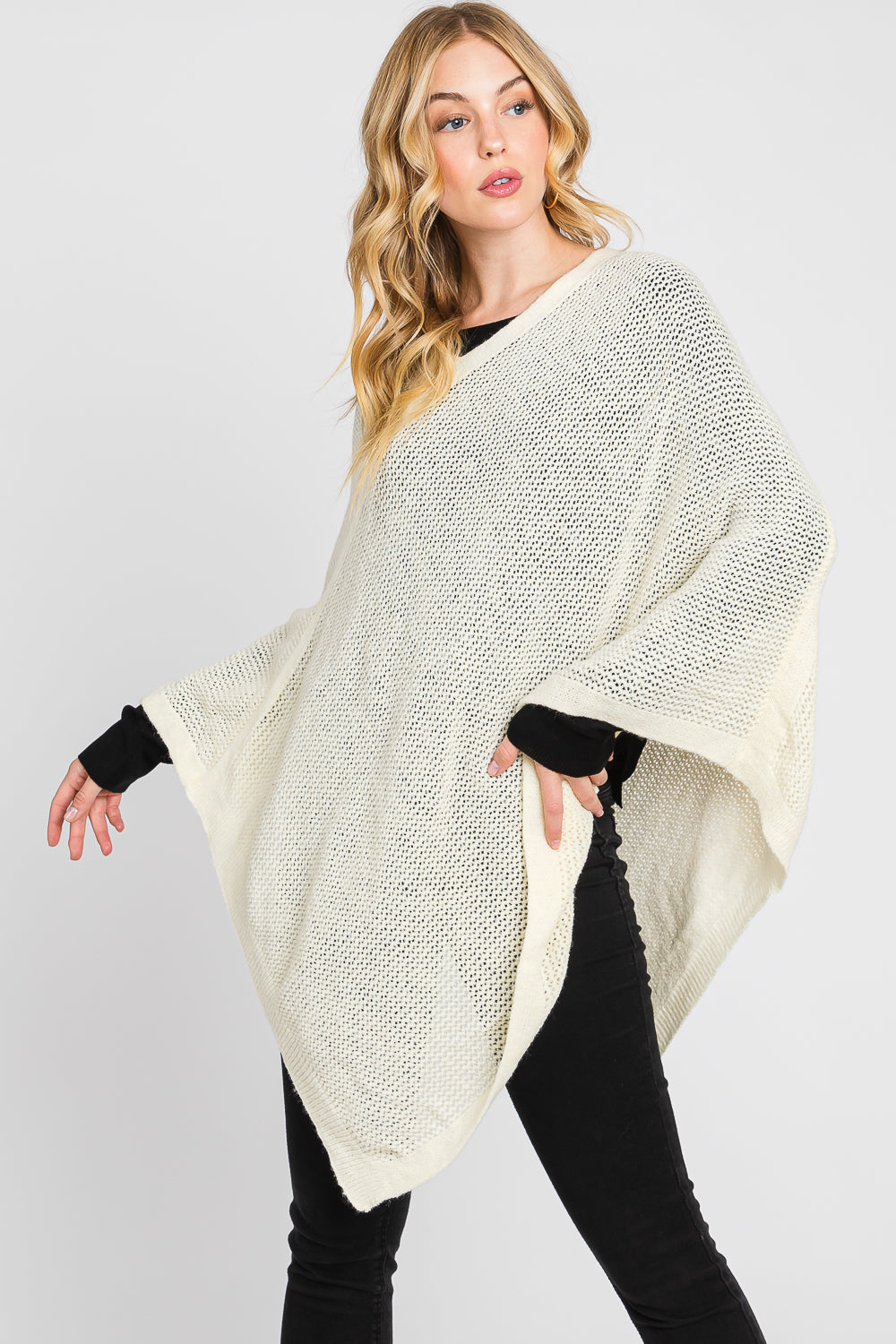Woman wearing a cream-colored poncho against a white background