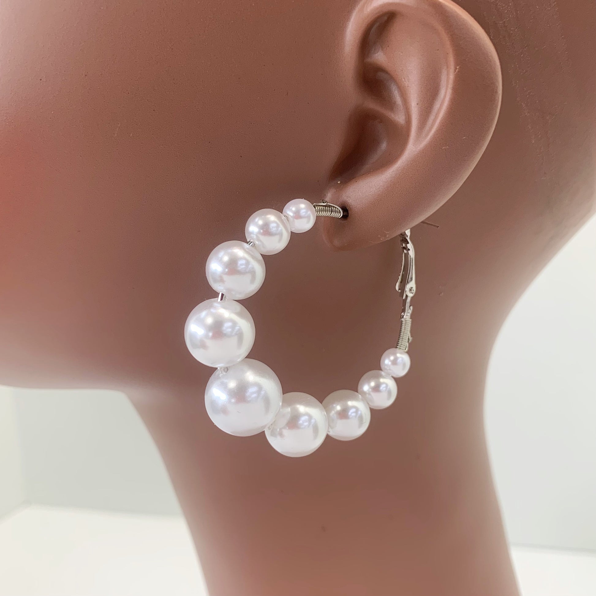 Oversized hoop earrings with graduated faux pearl accents in a glamorous boutique fashion style.