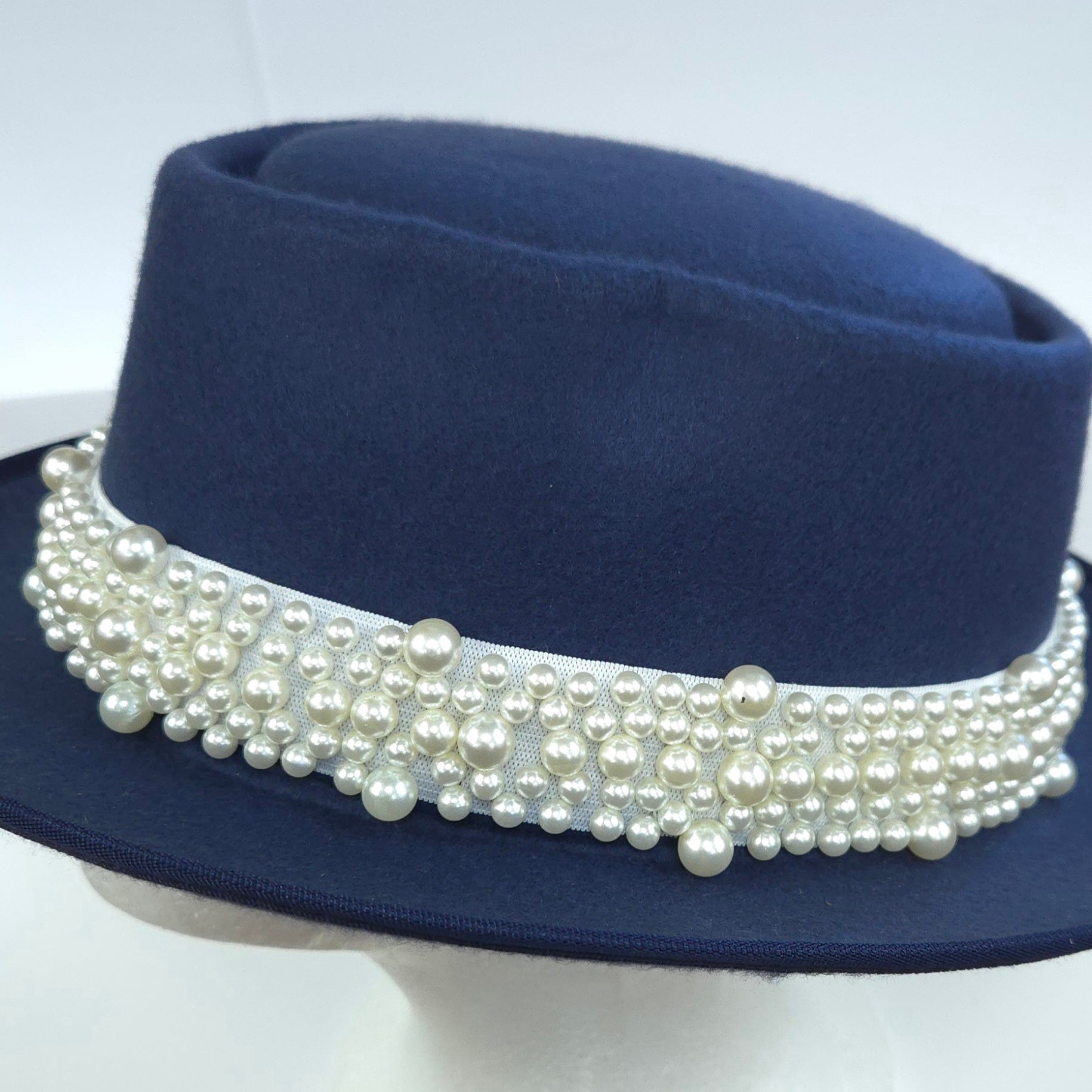 Navy blue hat with a pearl band on a white background