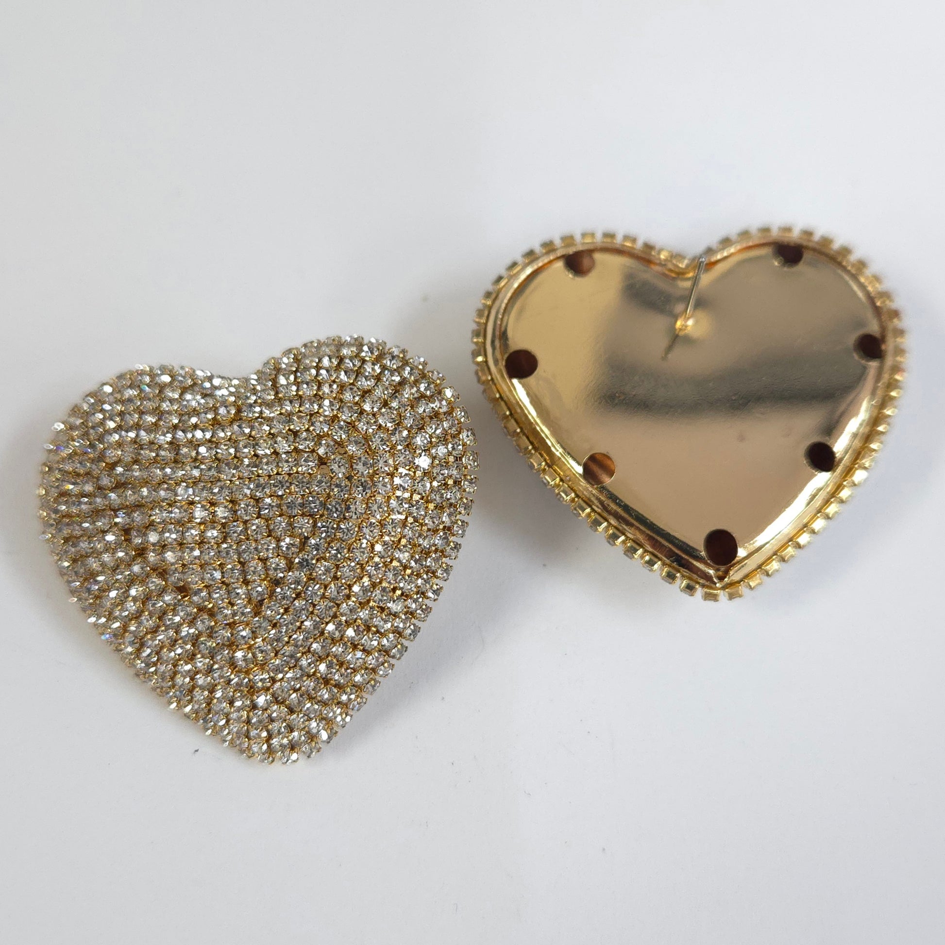 Two heart-shaped objects, one gold and one silver, on a white background