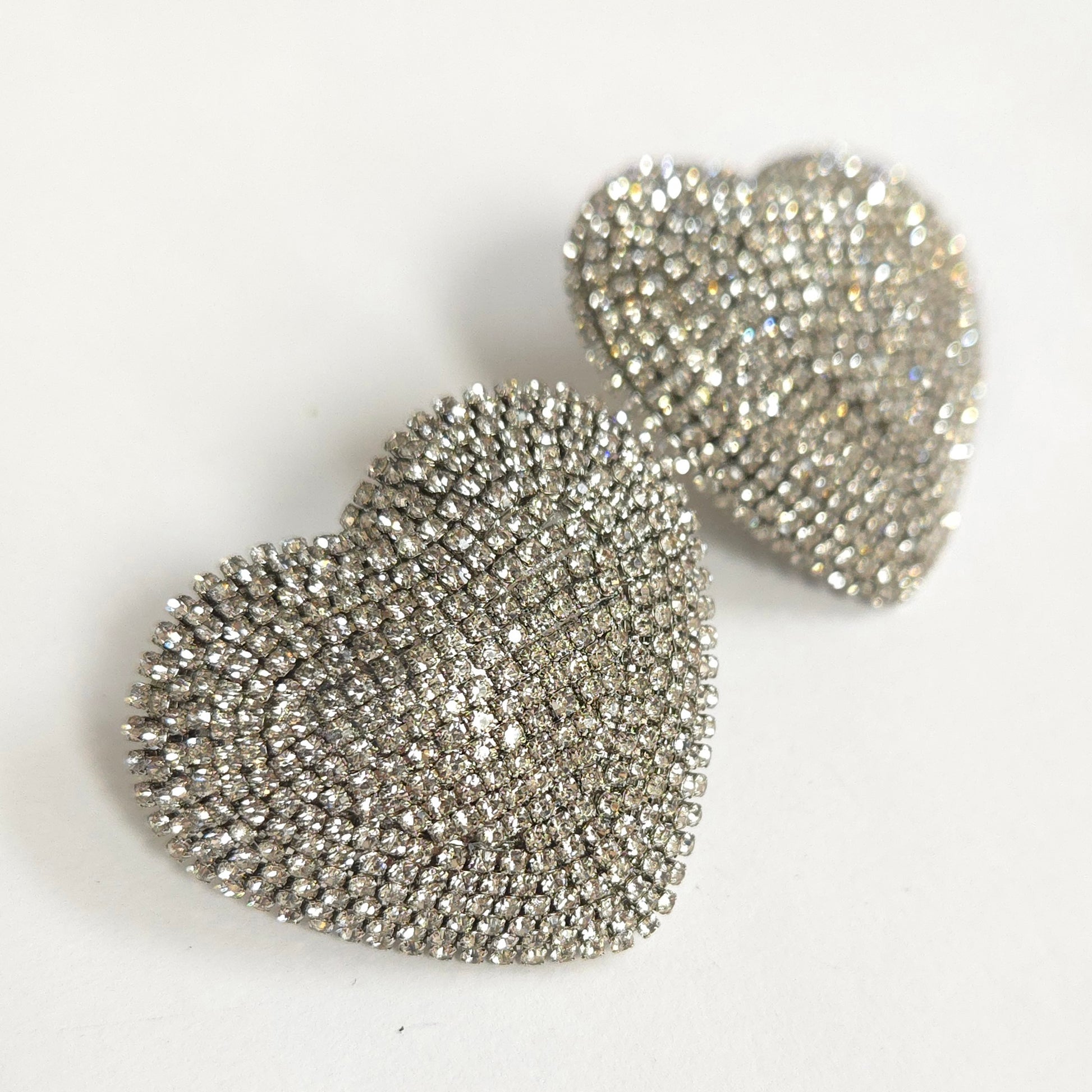 Heart-shaped silver earrings with sparkling stones on a white background