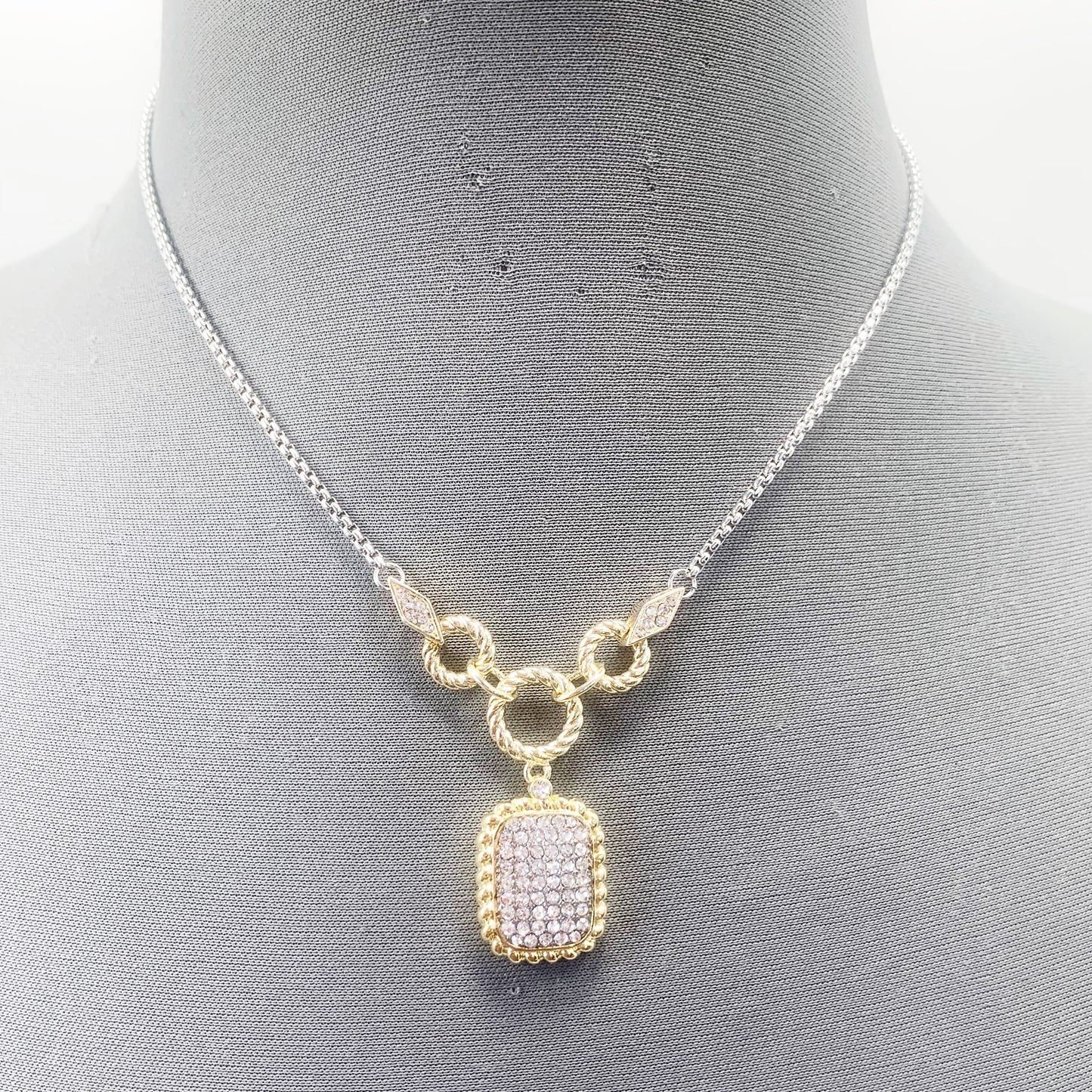A vintage necklace with a gold-tone frame and clear crystal pendant, displayed on a mannequin.