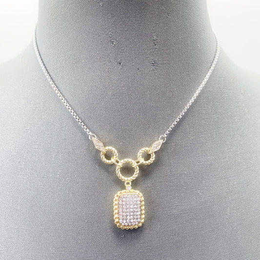 A vintage necklace with a gold-tone frame and clear crystal pendant, displayed on a mannequin.