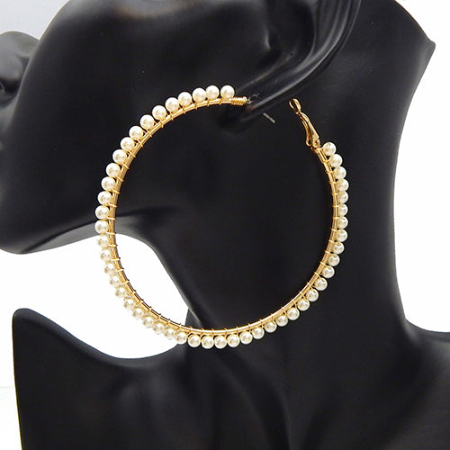 Large hoop earrings with delicate pearl trim detailing along the outer edge on a mannequin ear display