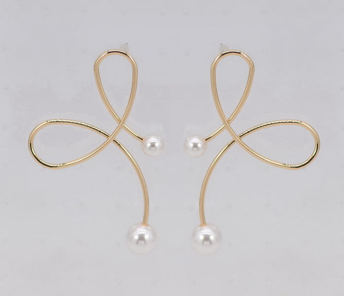 Gold earrings with pearl drops on a light gray background
