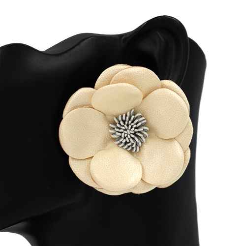 Beige flower-shaped brooch with a silver center on a black background
