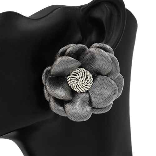 Gray flower-shaped brooch with a gold center on a black background