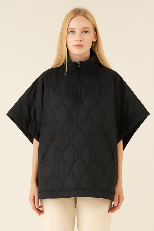 Woman wearing a black poncho with a textured pattern on a beige background