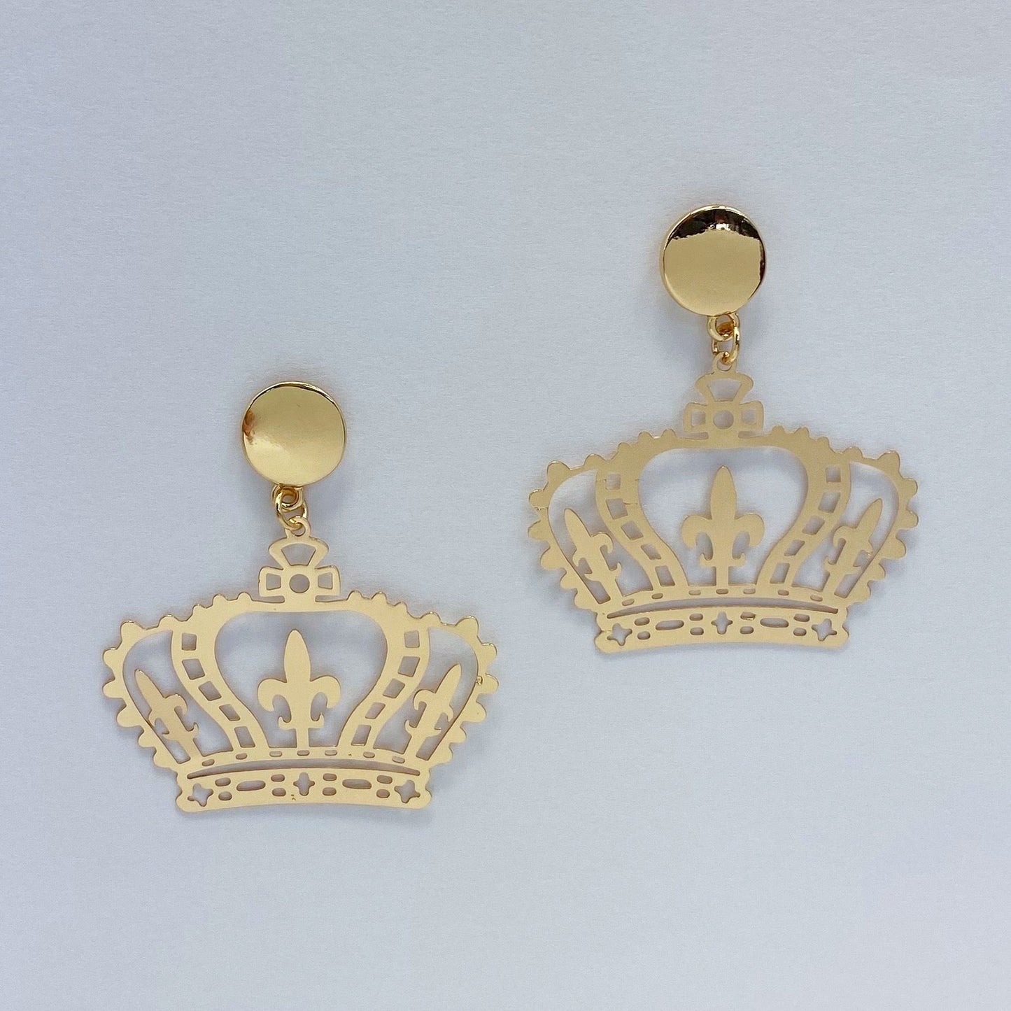 A pair of gold-colored metal earrings featuring a crown design.