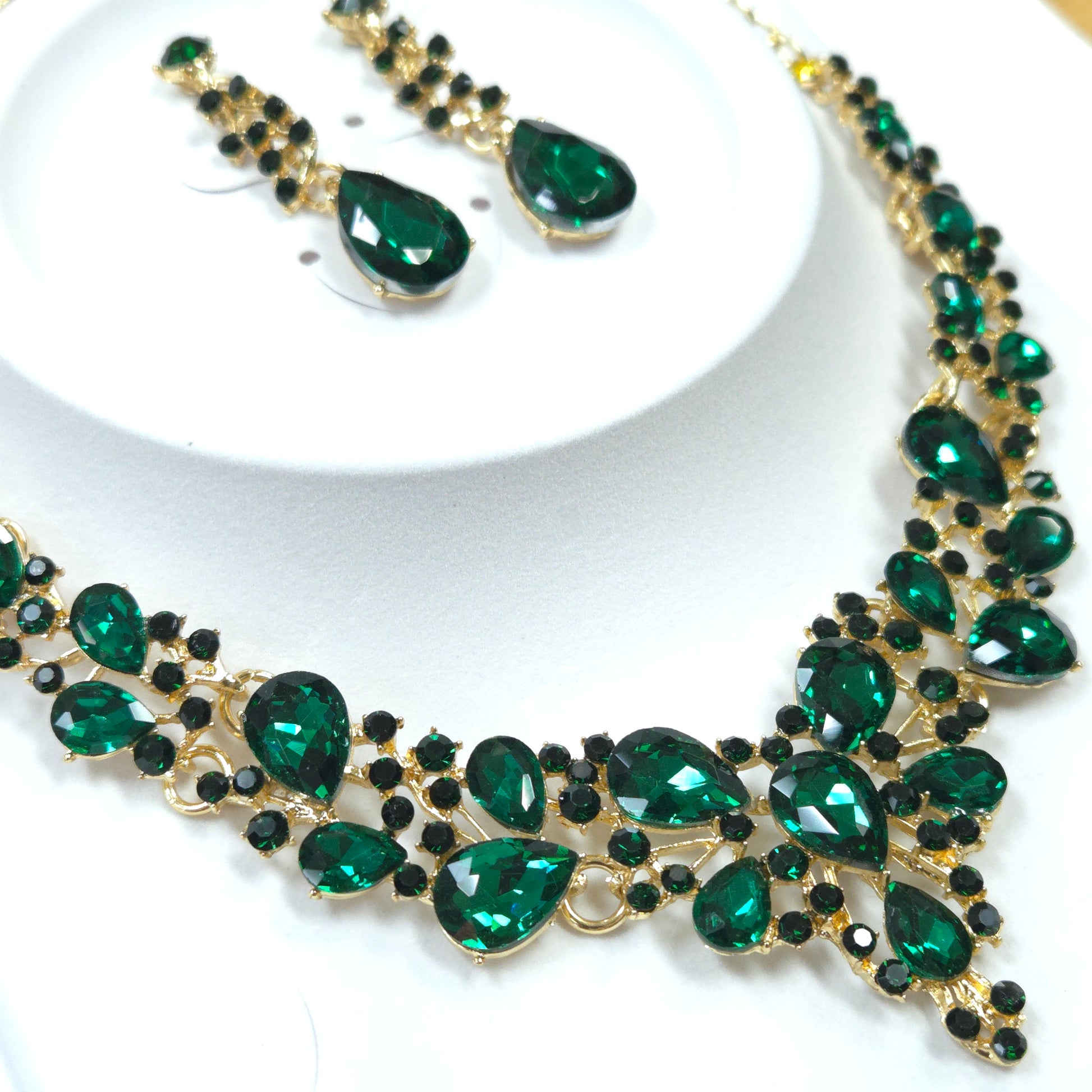 Jewelry set with green gemstones and gold accents on a white background