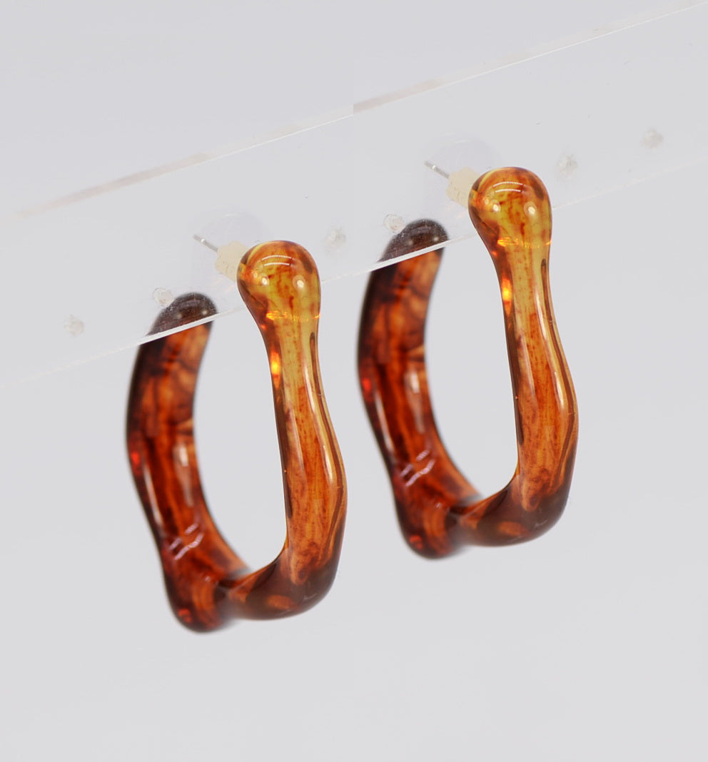 Pair of tortoiseshell hoop earrings on a light gray background