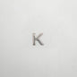 Silver letter 'K' charm on a white background