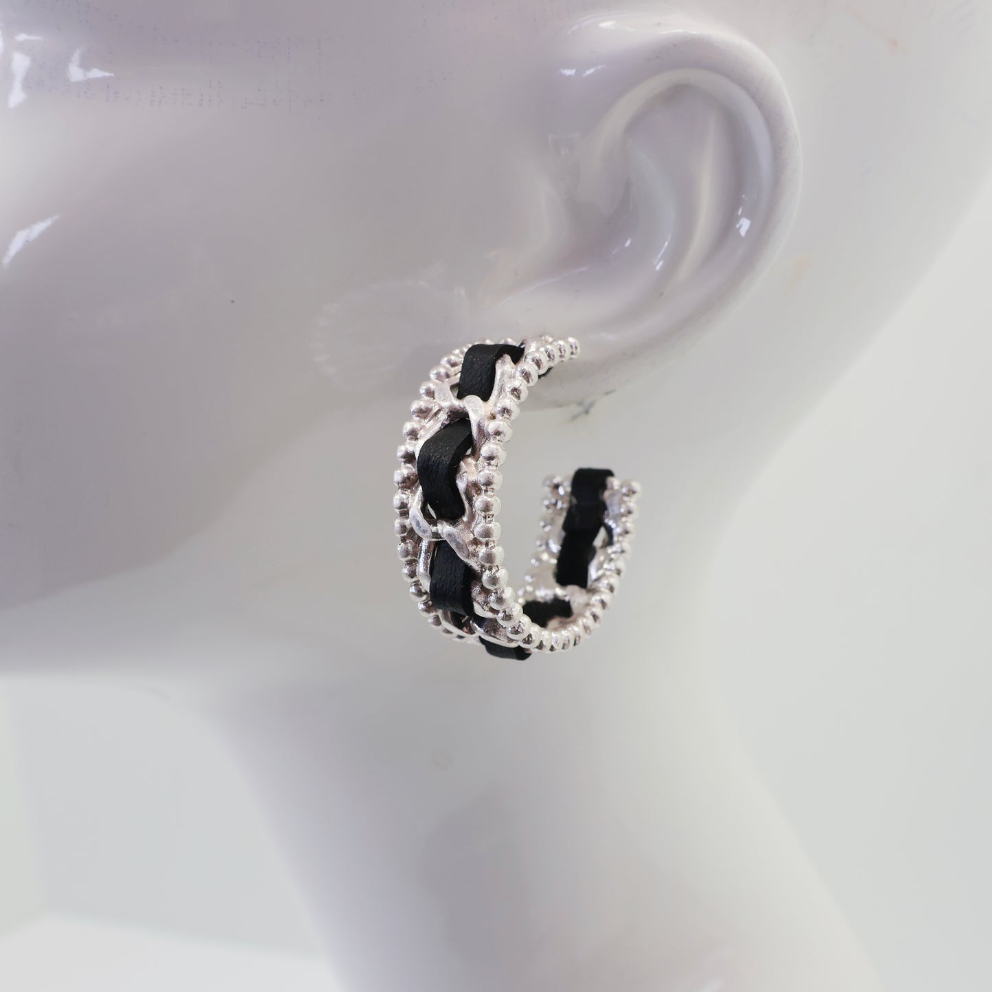 Braided chain hoop earrings with textured beaded edging and woven detail in a modern boutique fashion style.