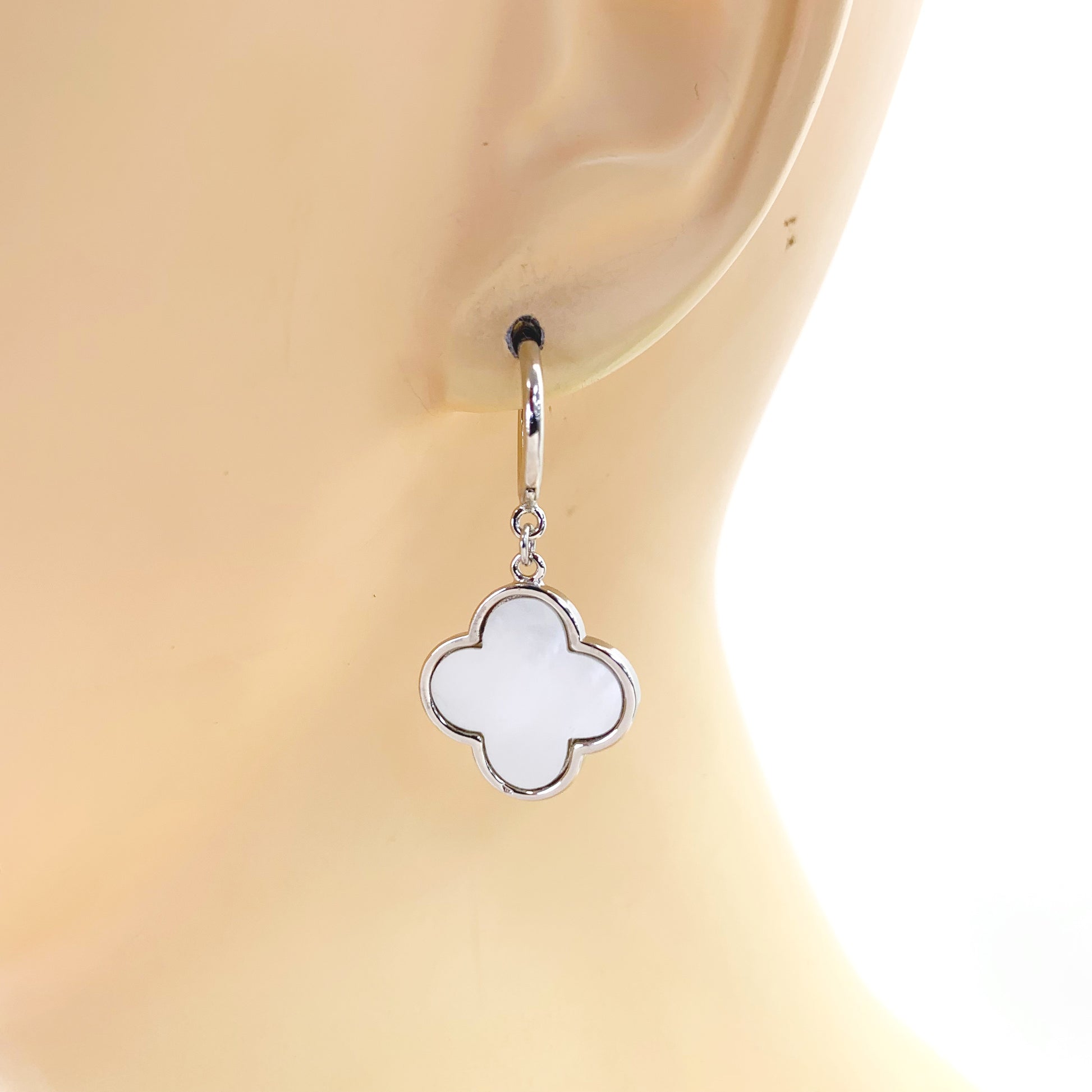 Hoop earrings with clover-shaped drop charms and polished trim in a chic boutique fashion style.