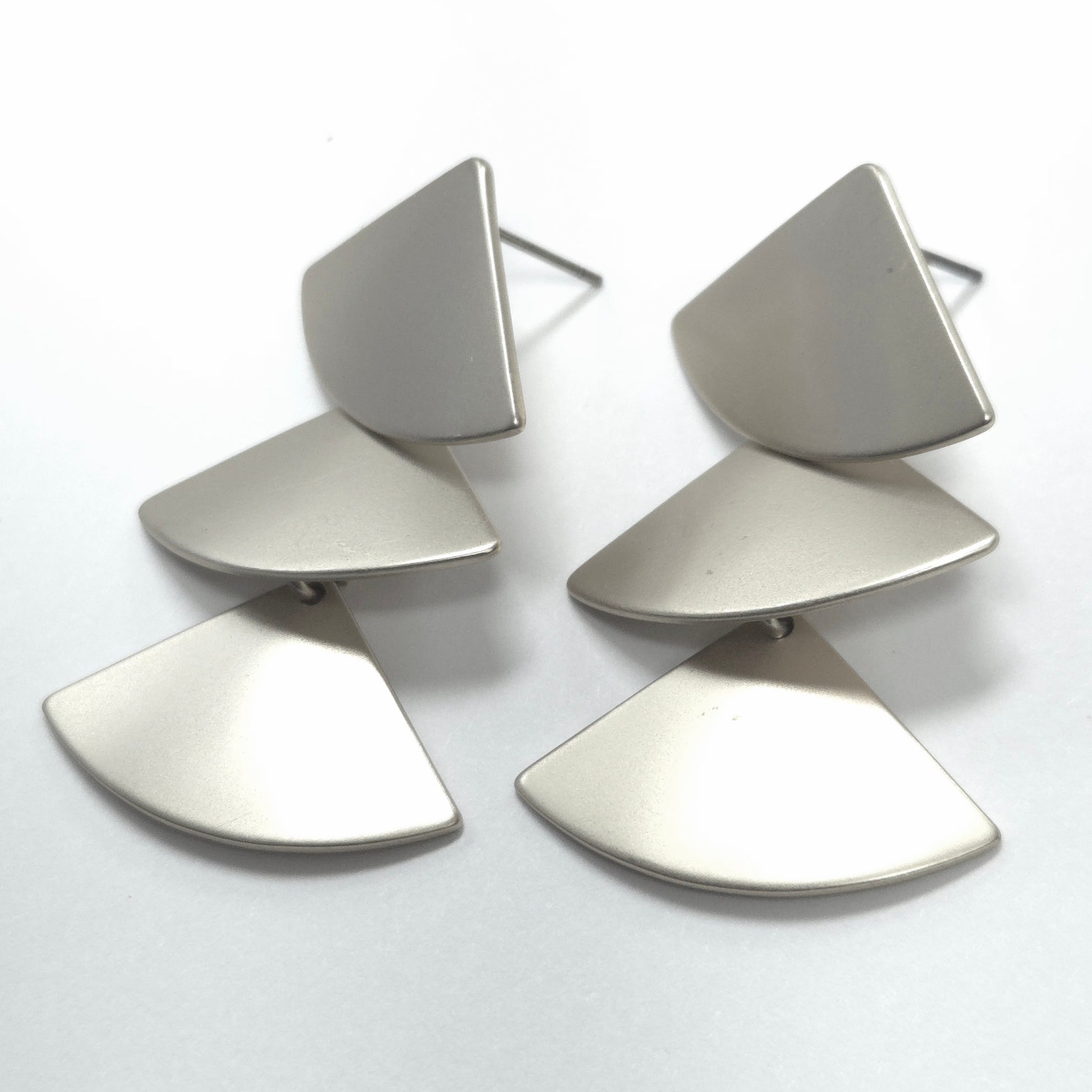 Pair of silver earrings with geometric design on a white background