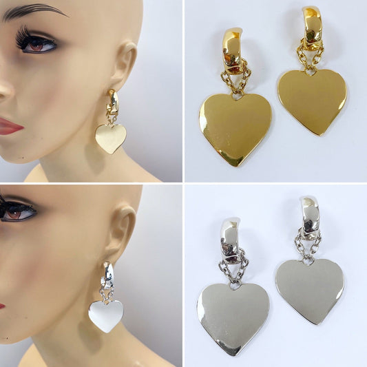 A mannequin head wearing a gold-colored heart-shaped dangle earring, with a close-up inset showing a silver-colored variation of the same earring.