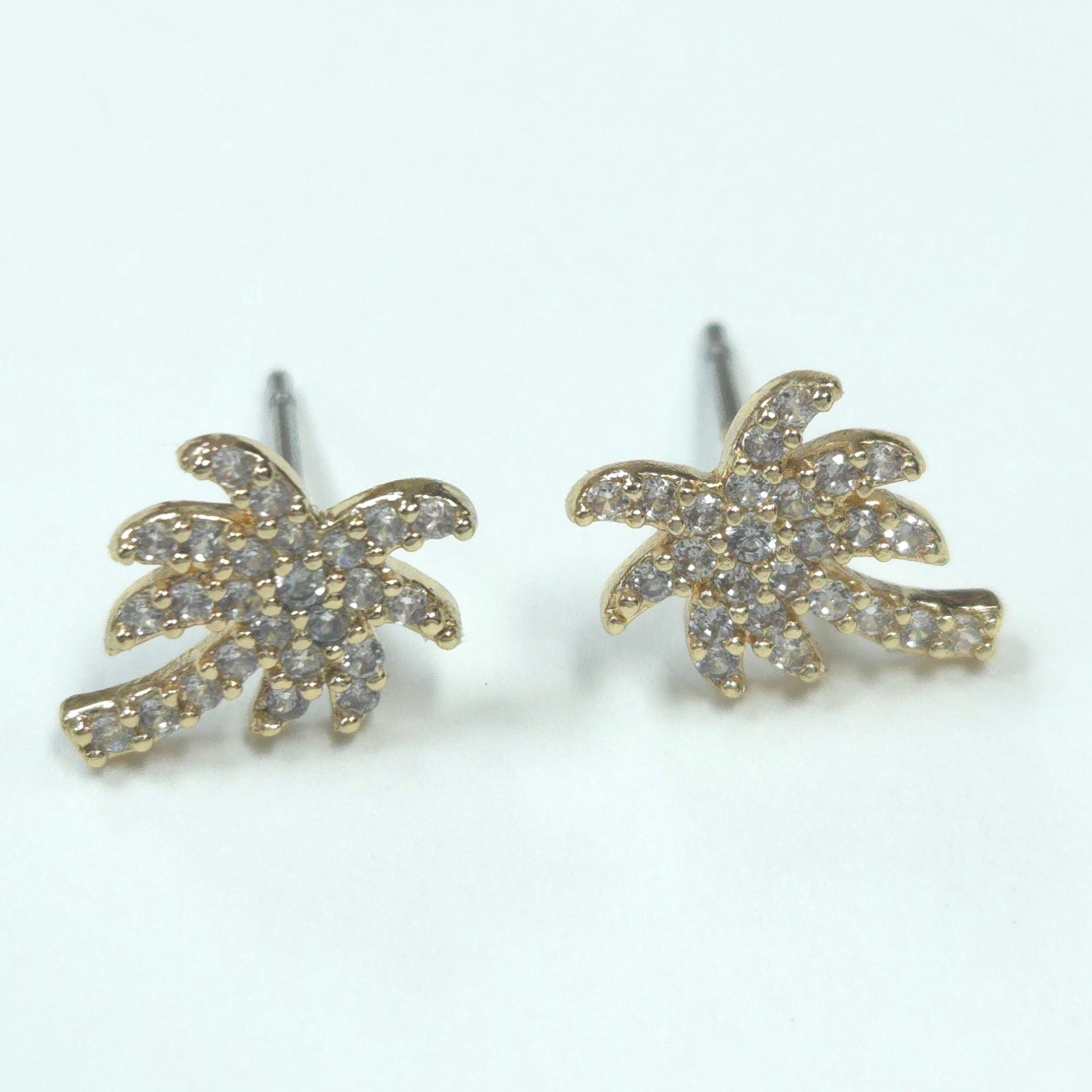 Gold palm tree earrings with clear stones on a white background