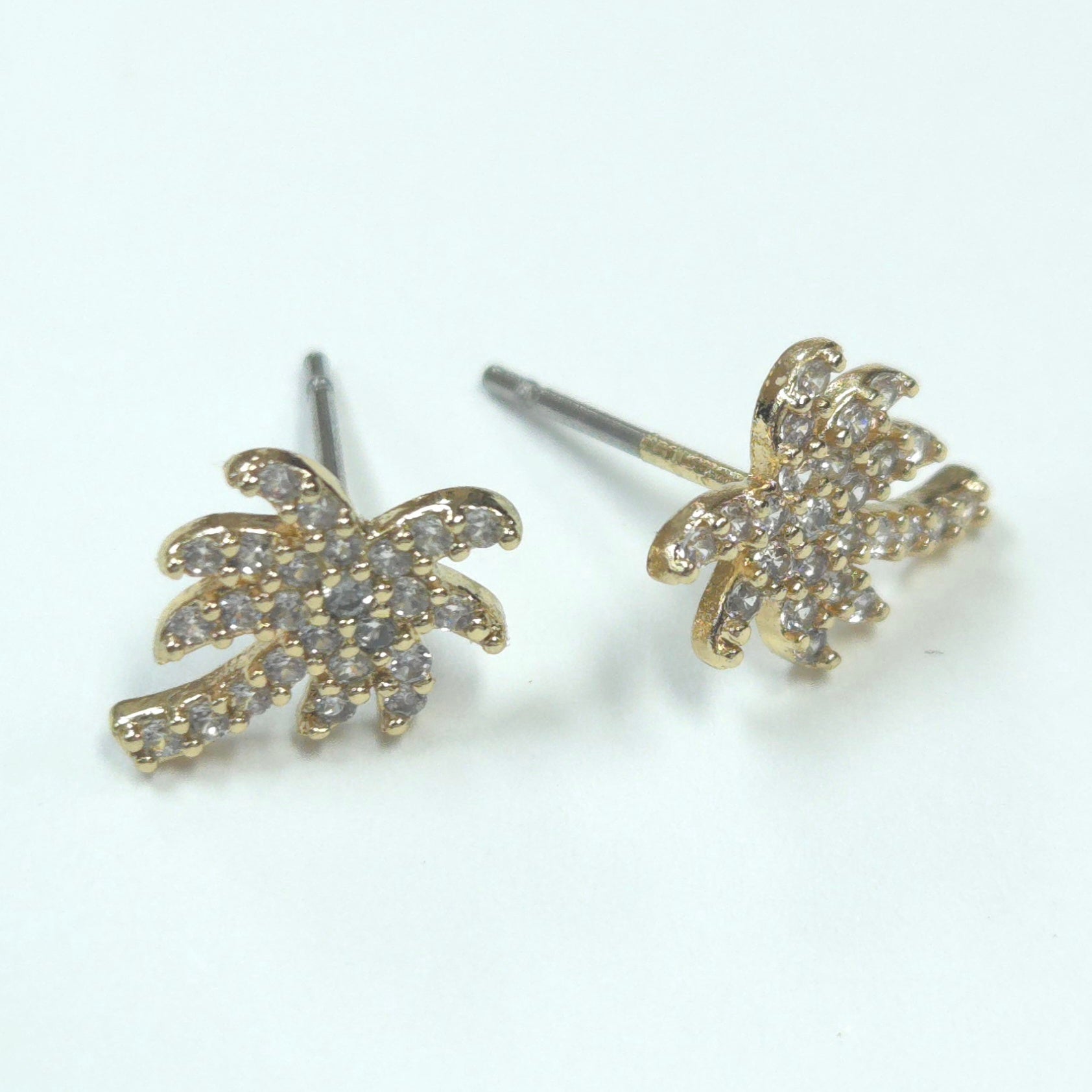Gold palm tree earrings with clear stones on a white background