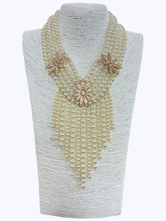 Layered faux pearl statement necklace featuring cascading pearl fringe strands with rhinestone floral accents and dramatic bib styling.