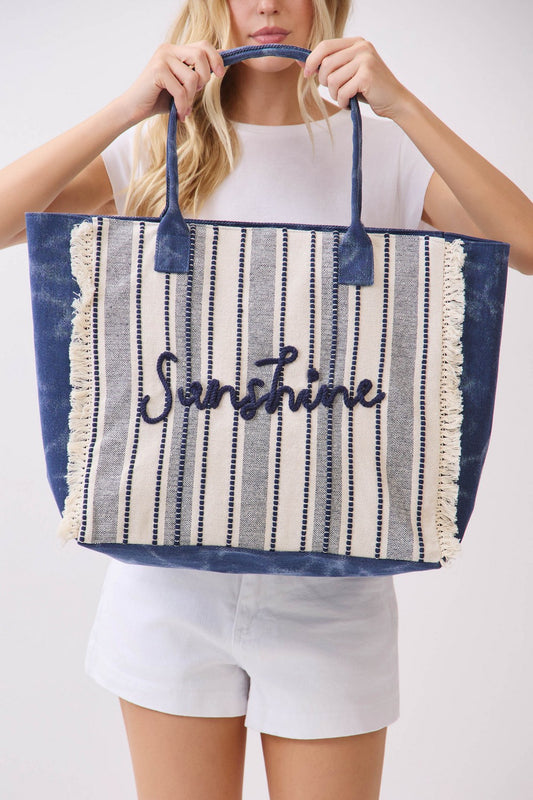 Person holding a striped tote bag with 'Sunshine' text on a white background