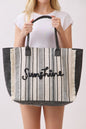 Person holding a striped tote bag with 'Sunshine' text on a plain background