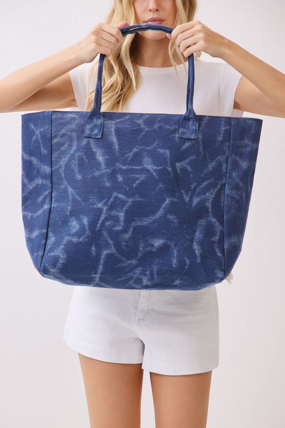 Person holding a blue tote bag with a white background