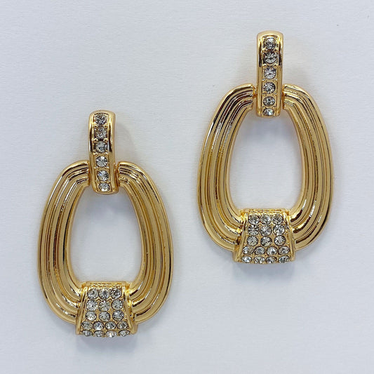 A pair of gold-toned oval-shaped dangle post earrings with rhinestone embellishments.