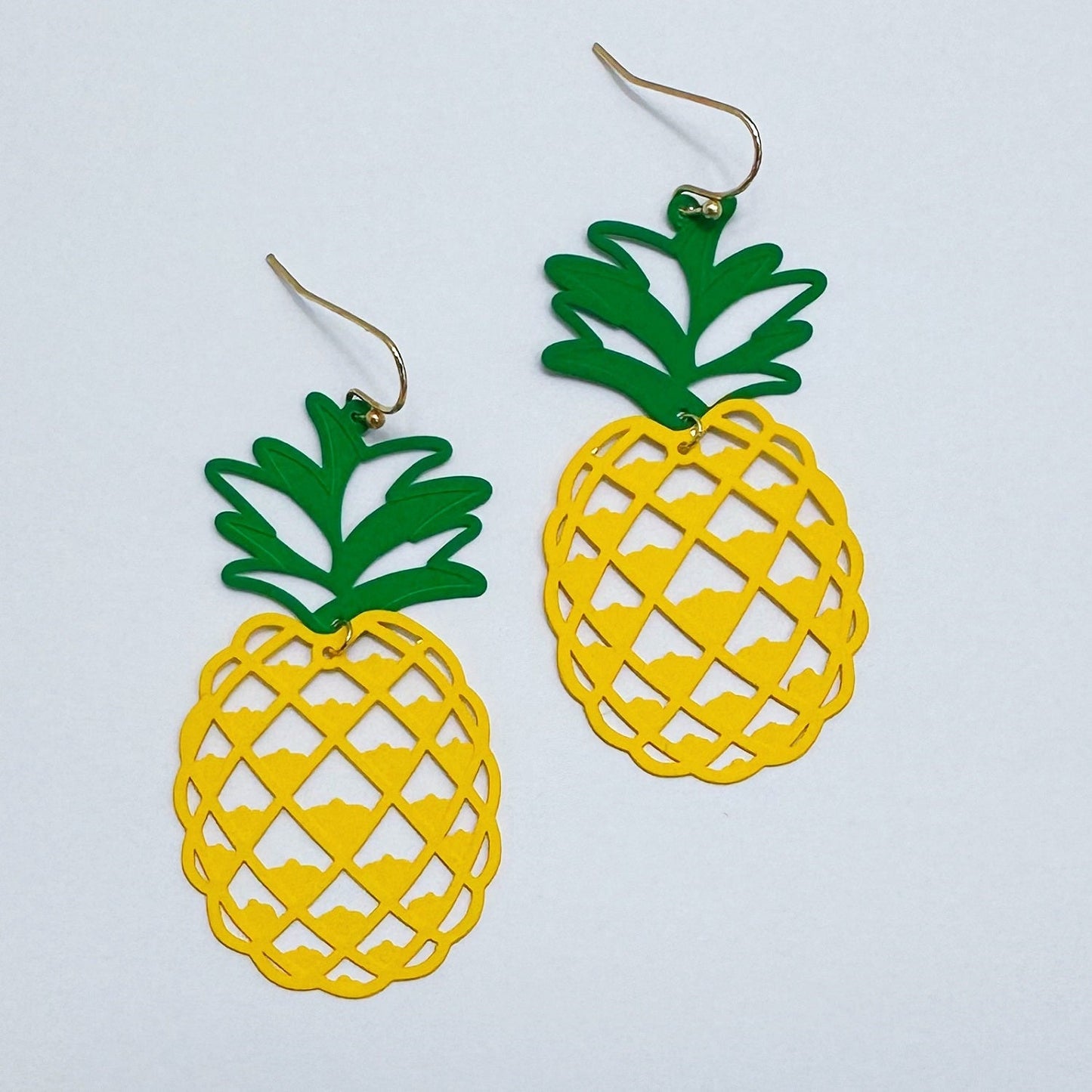 A pair of dangle earrings with a pineapple design, featuring a green and yellow color scheme on a white background.