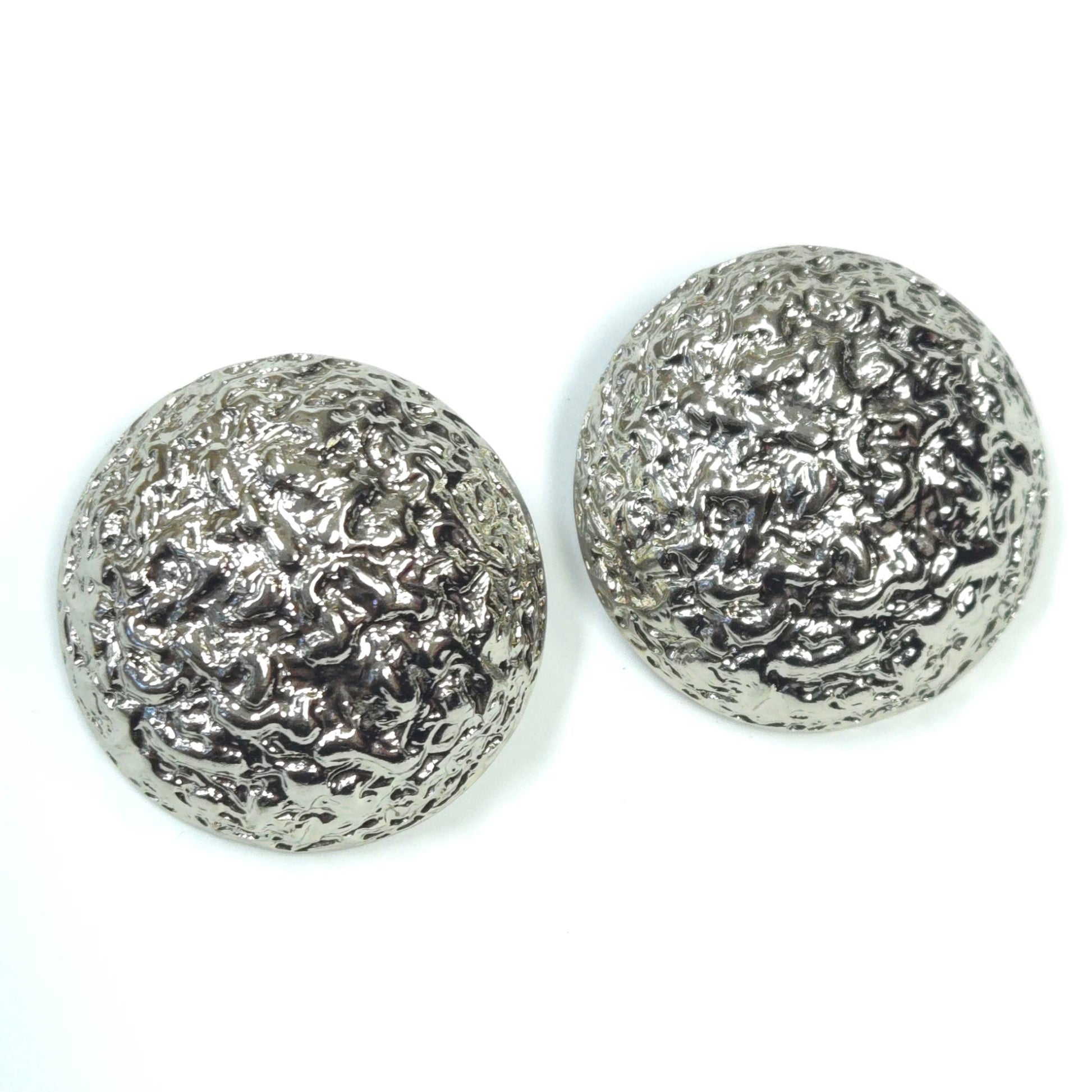 Pair of silver textured round earrings on a white background
