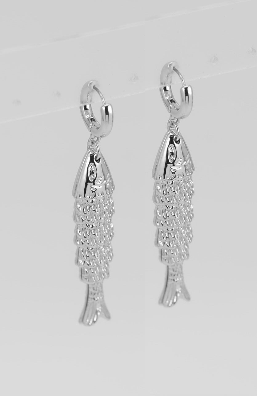 Silver fish-shaped earrings on a light gray background