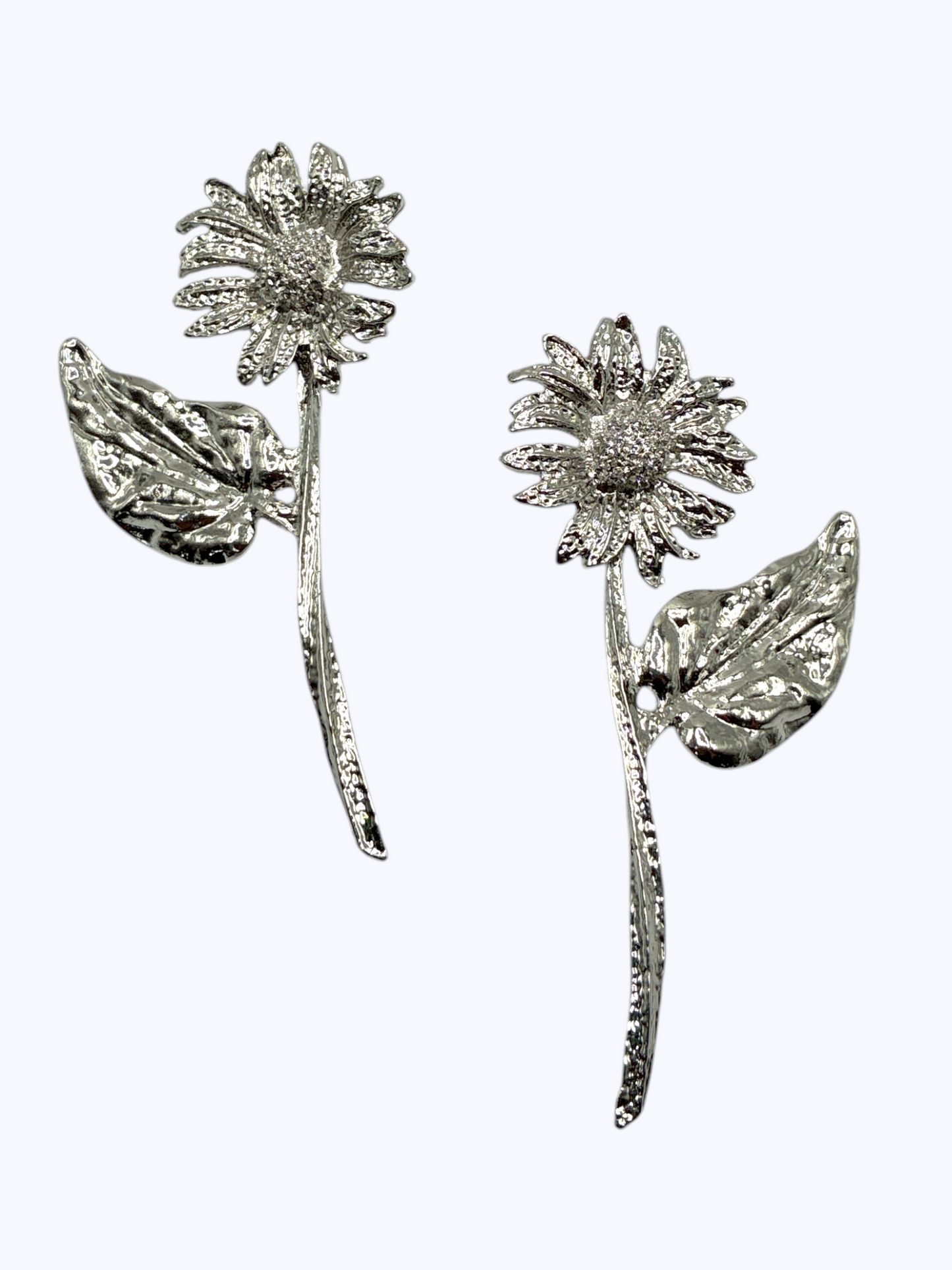 Silver floral statement earrings with textured daisy-inspired design and sculpted leaf accents for an elegant boutique-inspired look.
