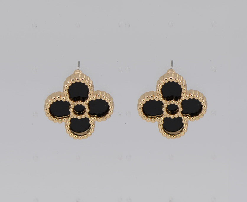 Pair of gold and black flower-shaped earrings on a light gray background