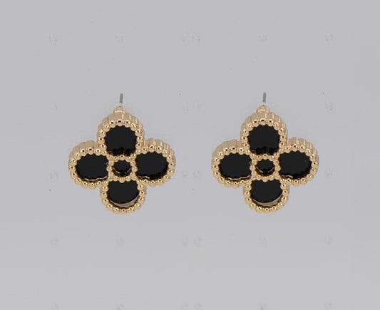 Pair of gold and black flower-shaped earrings on a light gray background