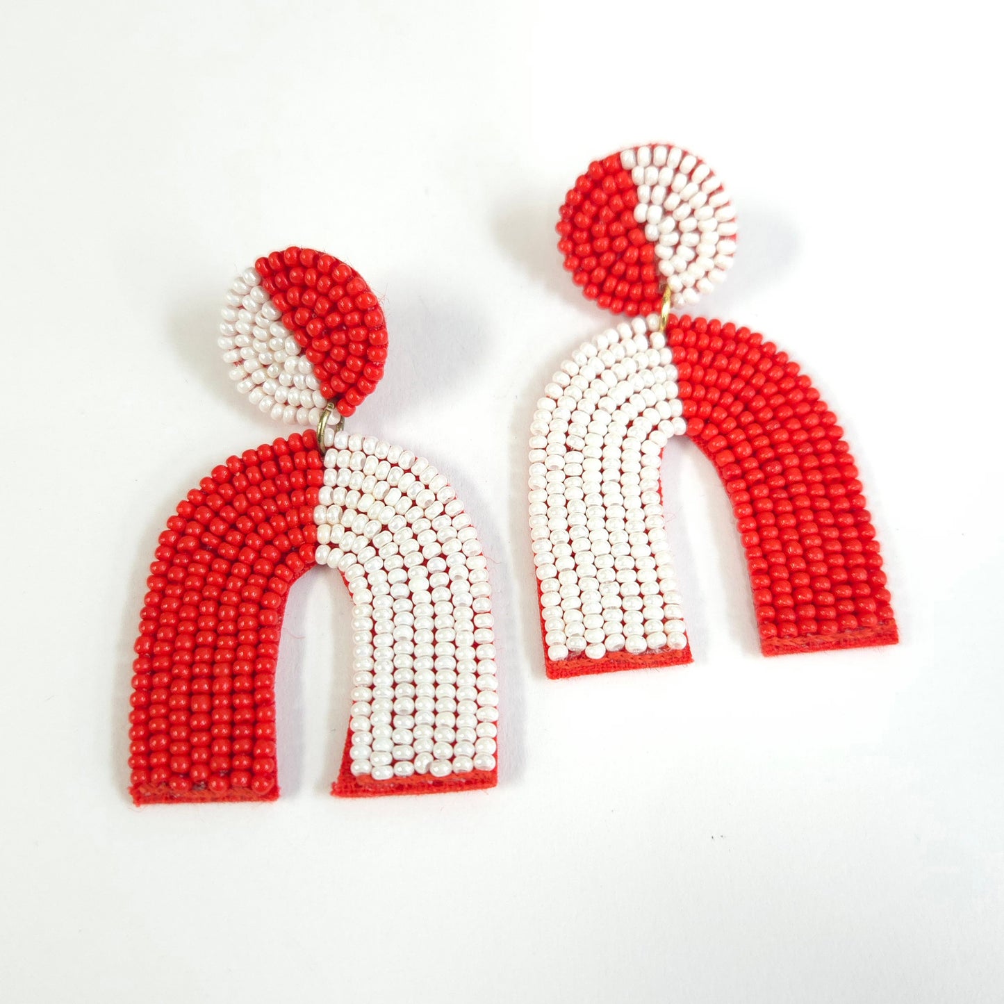 Pair of red and white beaded earrings on a light gray background