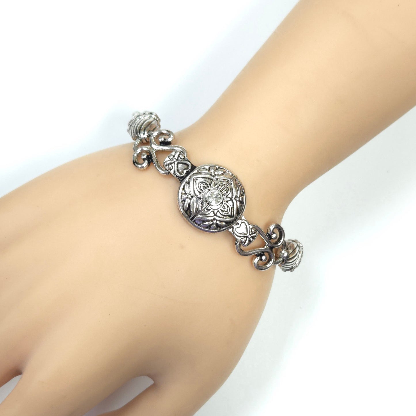 Silver bracelet with intricate design on a wrist against a white background