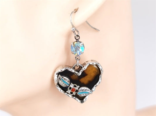 Heart-shaped earrings with a tiger eye stone on a mannequin ear.