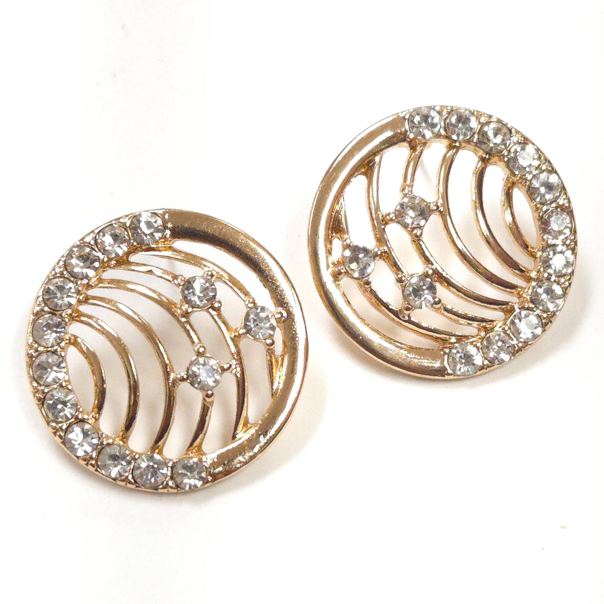 Gold earrings with circular design and embedded crystals on a white background