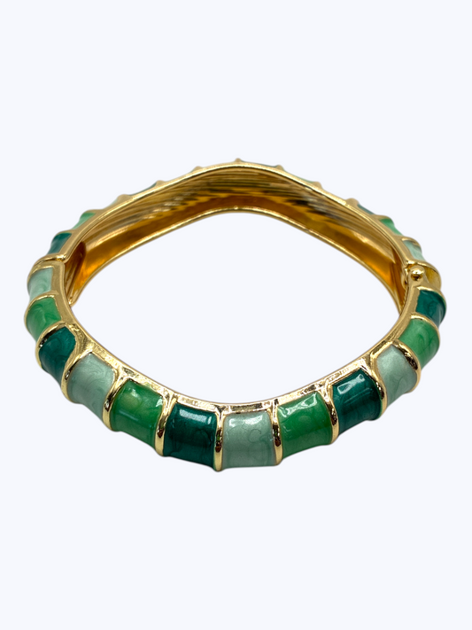 Gold ring with green gemstones on a white background