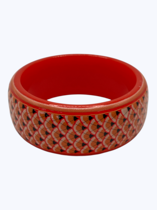 Red bangle with a patterned design on a white background