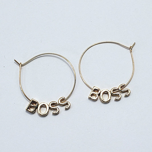 A pair of gold-colored hoop earrings with the word 'BOSS' written in a retro font, displayed in three different views on a white background.