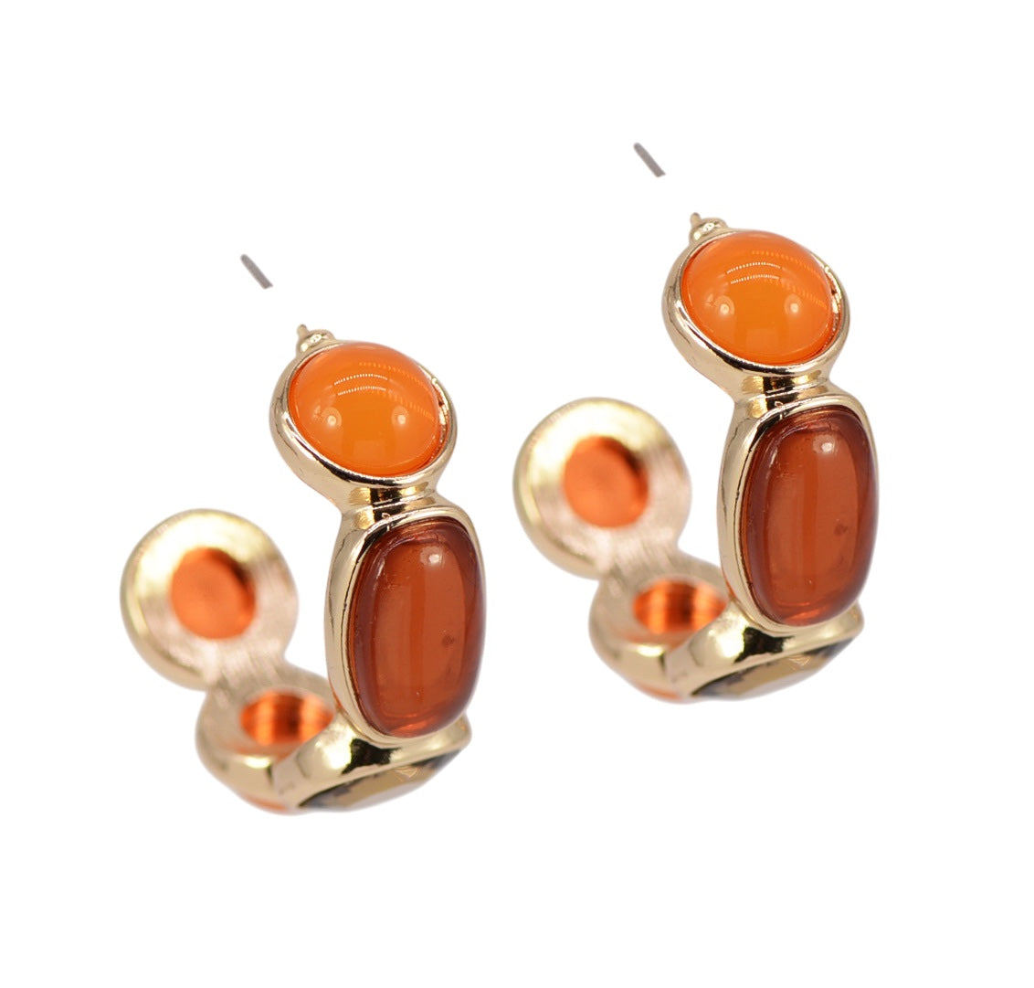 Gold earrings with orange and brown stones on a white background
