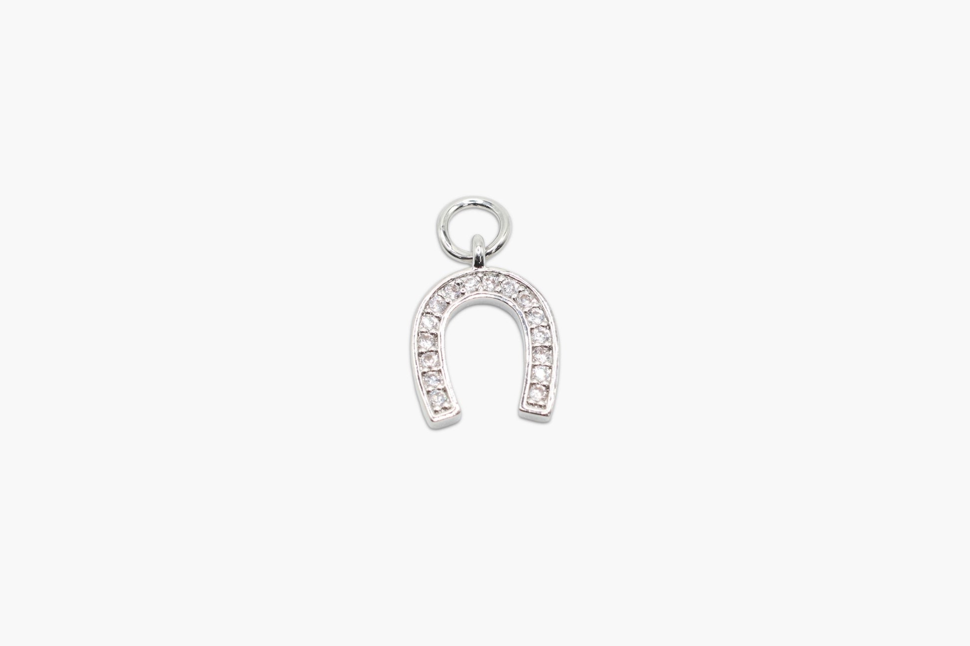 Silver horseshoe charm with embedded stones on a white background
