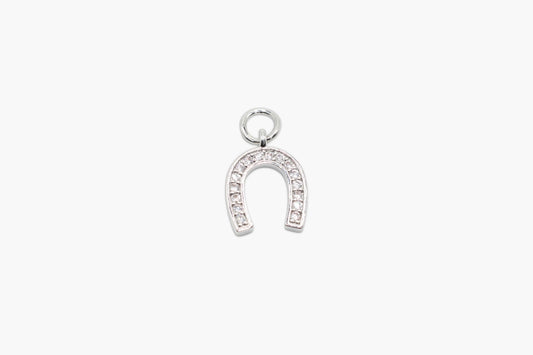 Silver horseshoe charm with embedded stones on a white background