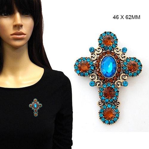 Decorative cross brooch with blue and orange gemstones on a mannequin and white background