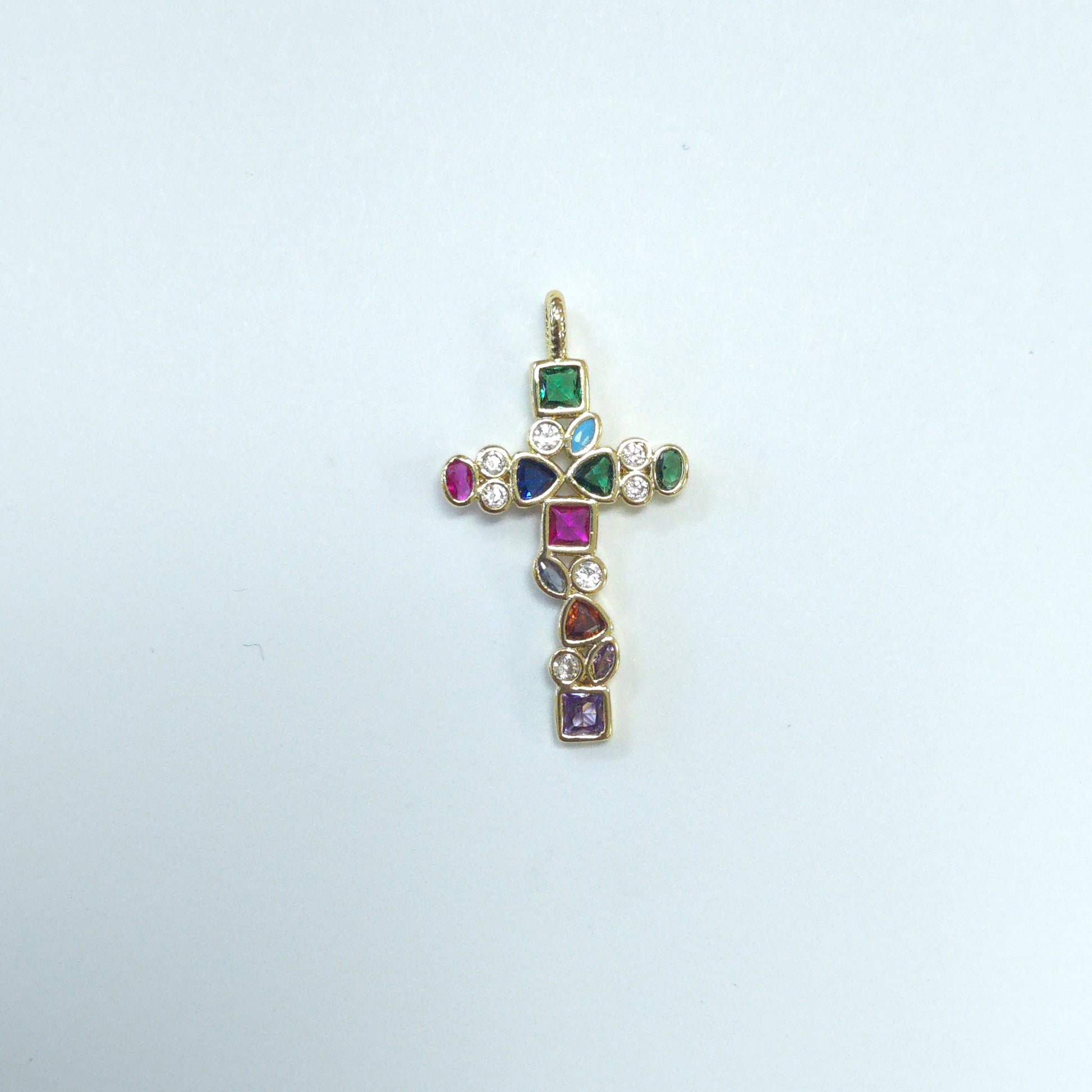 Gold cross pendant with colorful gemstones on a light gray background