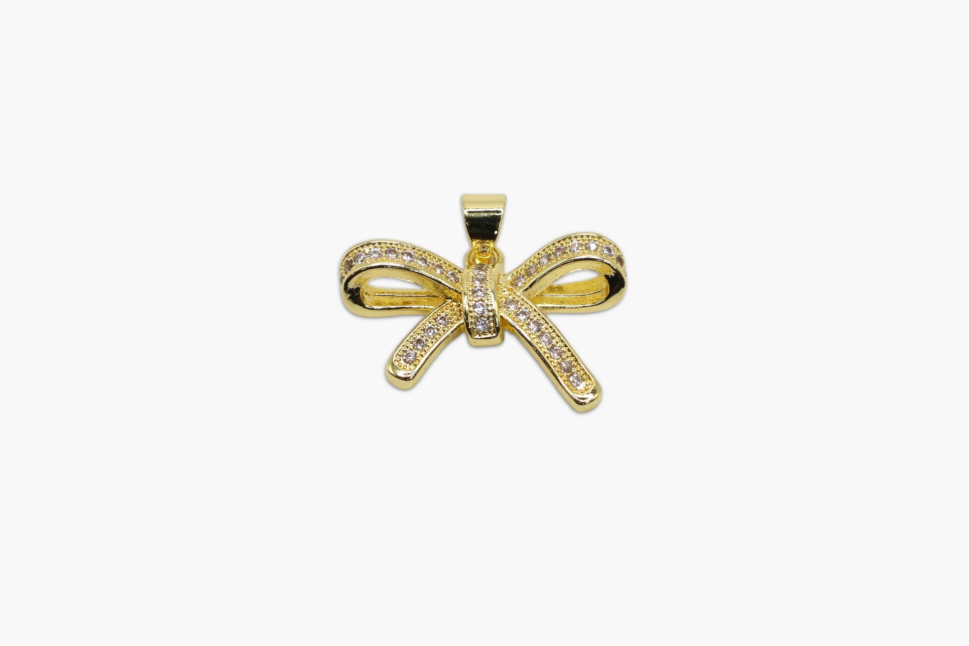 Gold bow-shaped pendant with clear stones on a white background