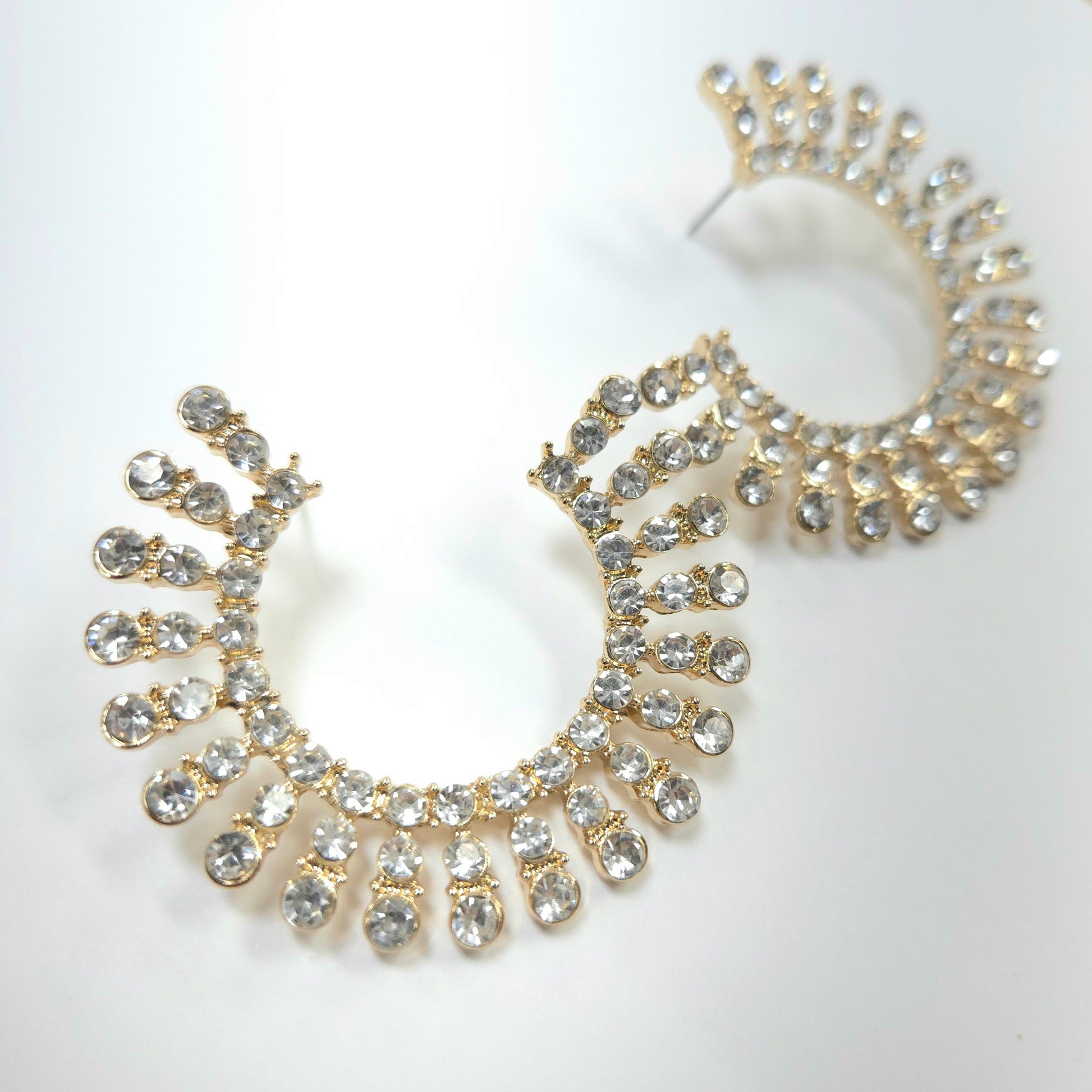 Gold and crystal hoop earrings on a white background