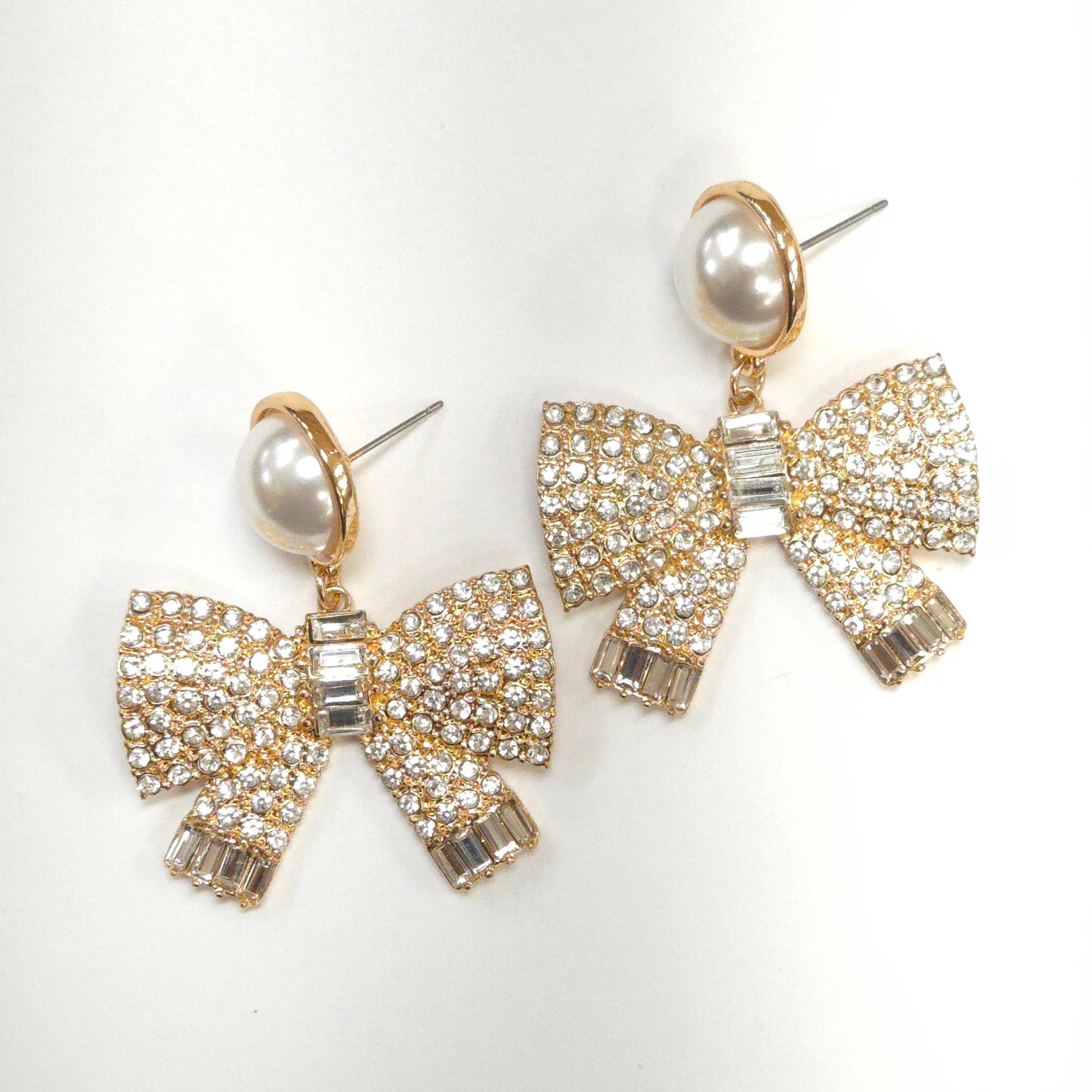 Bow-shaped earrings with pearl centers on a white background
