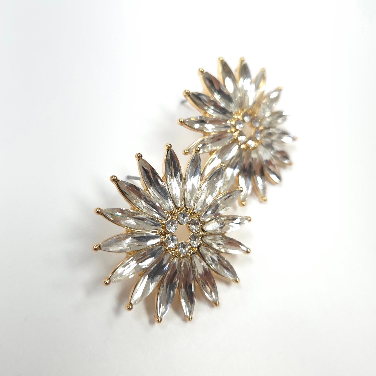 Pair of star-shaped earrings with clear stones and gold accents on a white background